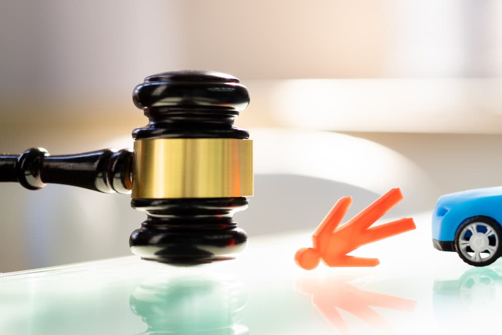Legal Process and Timeline for Pedestrian Accident Claim Settlements Gavel next to pedestrian accident figure and toy car representing legal process and settlement timelines for pedestrian accident claims.