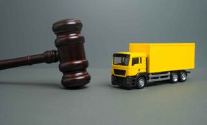 Judge’s gavel next to a yellow delivery truck symbolizing commercial trucking law and legal liability in transportation cases.